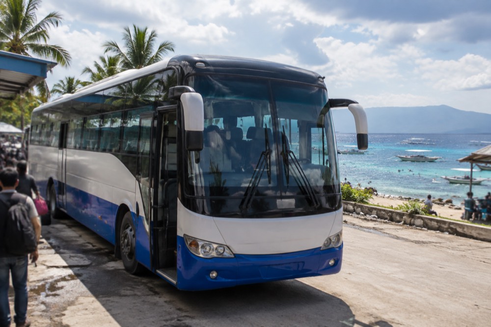 A long-distance bus parked at a busy Philippine bus terminal in the morning