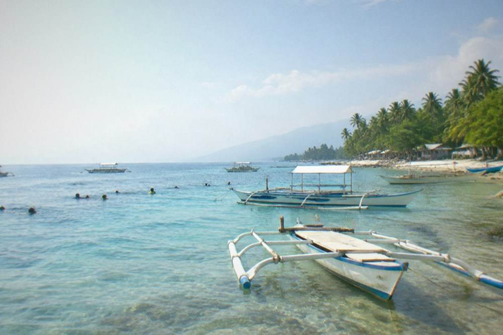 Wooden outrigger boats waiting at the Tan-awan beach in Oslob in early morning light