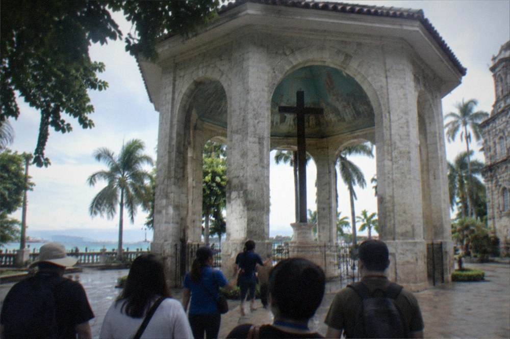 A guide leading a small group of visitors along a shaded street in Cebu City