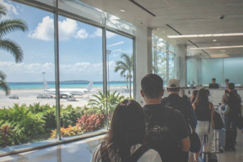 Travelers queuing at an immigration counter in a bright airport arrivals hall
