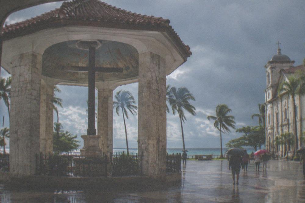 A tropical beach under gathering monsoon clouds with palm trees bending in the wind