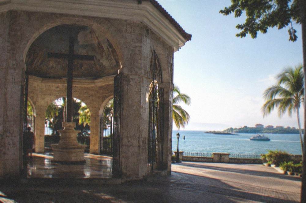 A ferry crossing a calm tropical channel toward an island with resorts along the shore