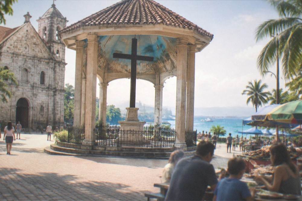 A family sharing grilled food at an outdoor table near a market street