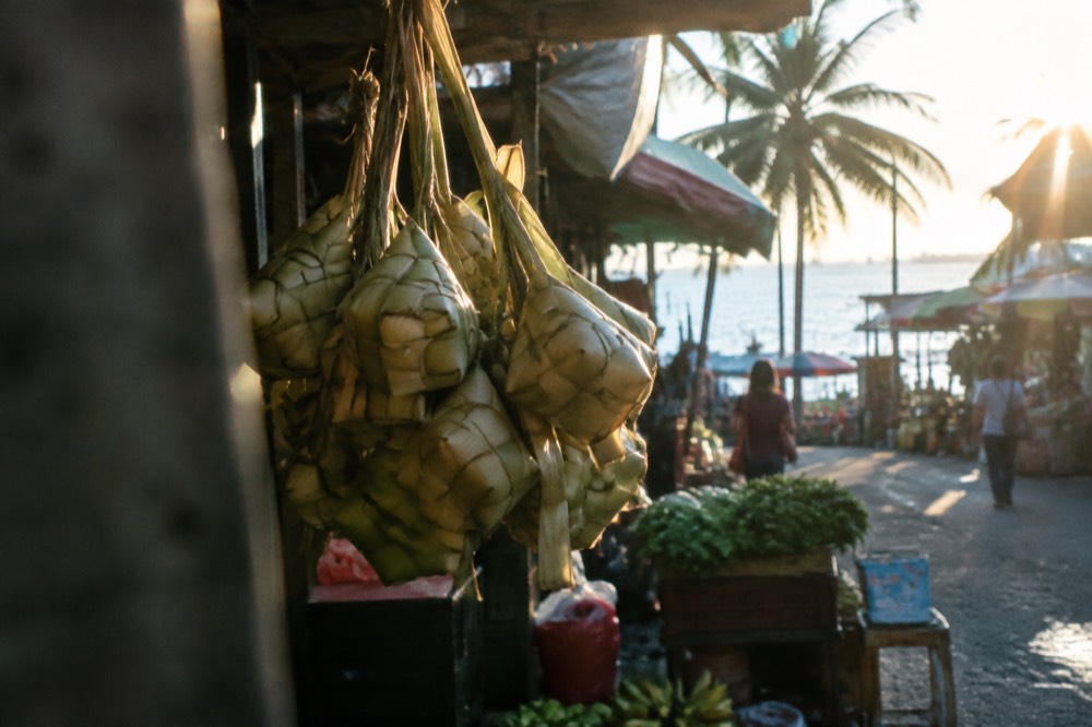 Woven palm-leaf rice pouches hanging in a bundle at a market stall