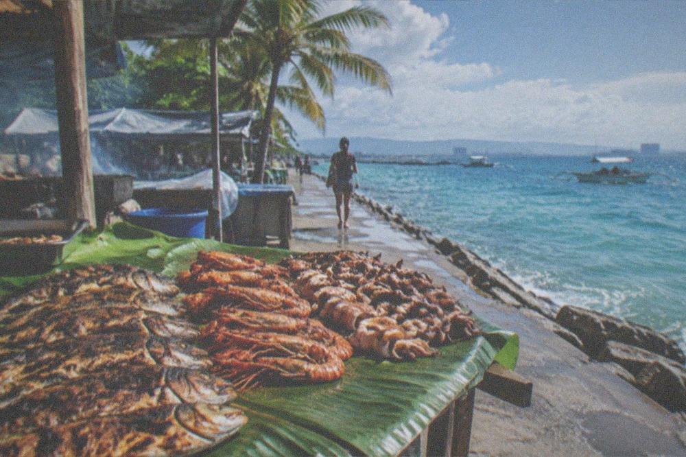 Grilled fish, prawns and squid laid out on a banana leaf at a seaside eatery