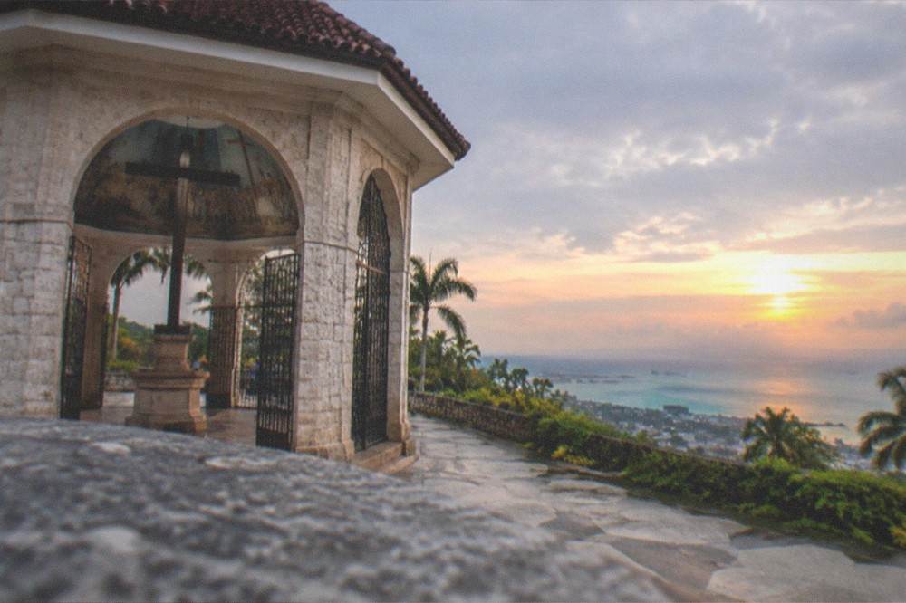 Sunset over the sea from a hilltop viewpoint with the city lights beginning to appear below