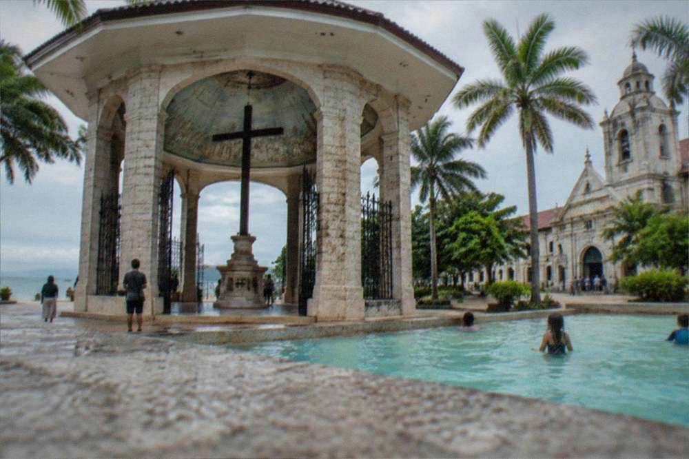 Children playing in a shallow resort pool under palm trees