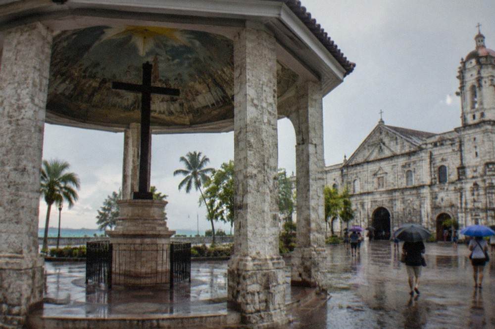 Tourists walking with umbrellas along a wet street in Cebu City during a rain shower