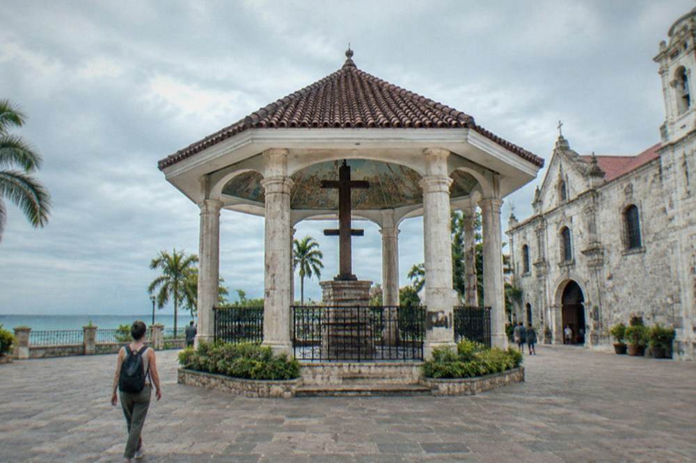 A traveller with a small backpack walking past colonial-era stone buildings in downtown Cebu City