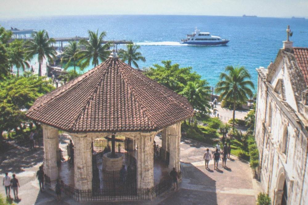 A fast craft ferry departing Cebu City's pier area with passengers on the open deck