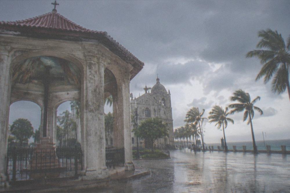 Heavy rain falling on an empty street in Cebu City with palm trees bending in the wind