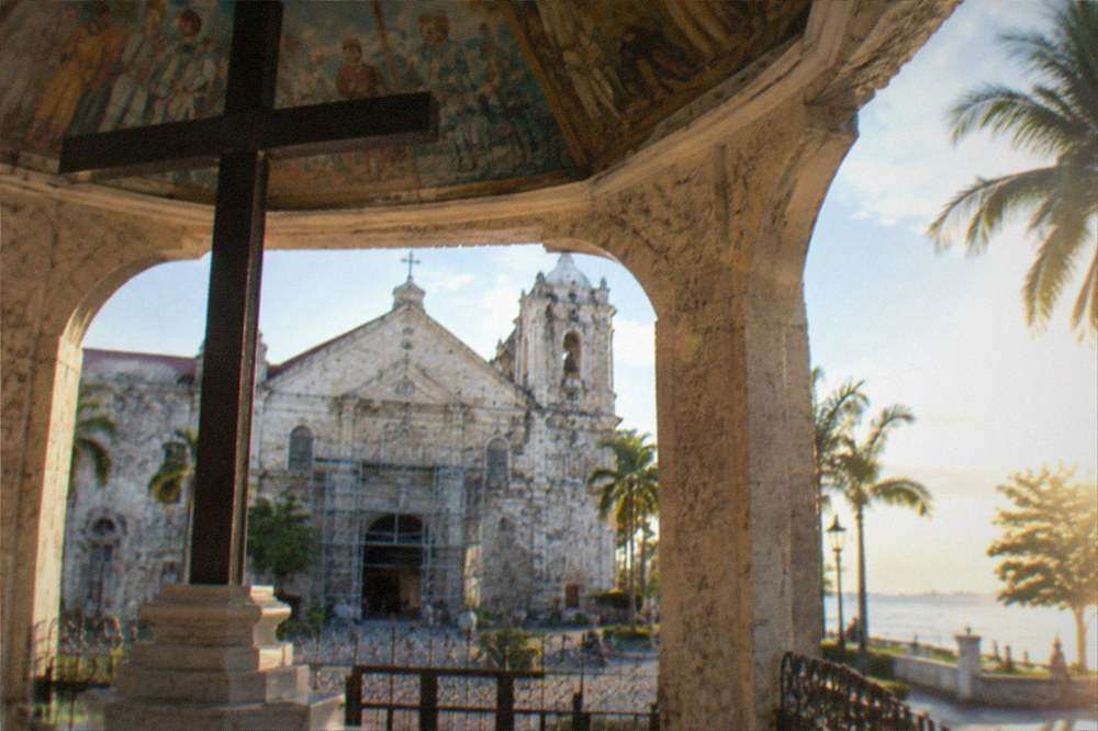 A coral-stone church facade in northern Cebu with visible cracks and scaffolding at the entrance