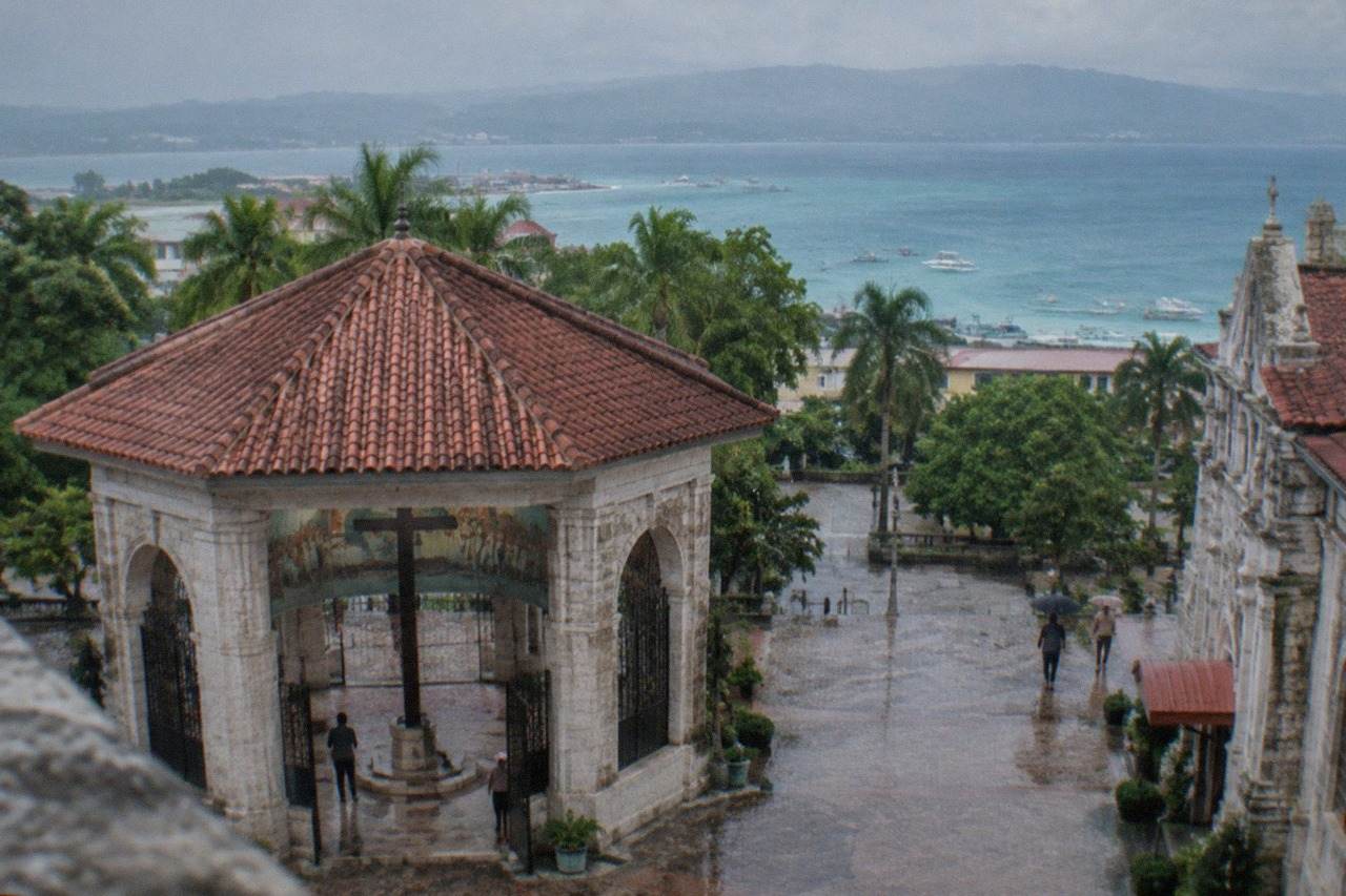 A view across Cebu island showing green hills meeting the sea with small boats near the shore