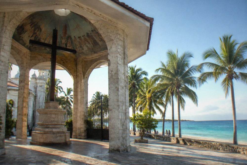 A white sand beach with turquoise shallows and a line of palm trees along the shore