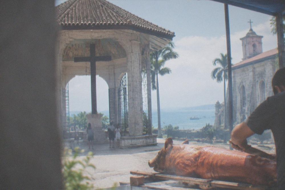 A whole roasted pig with crisp golden skin being sliced at an outdoor market stall