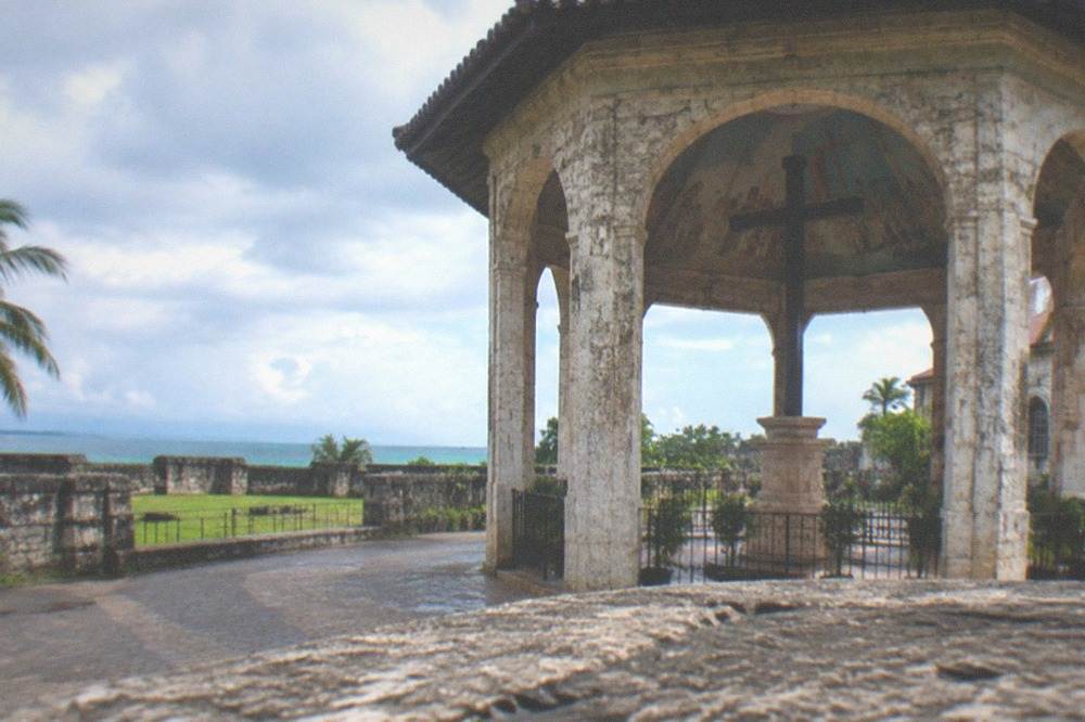 A coral stone fort wall with a grassy courtyard under a blue sky