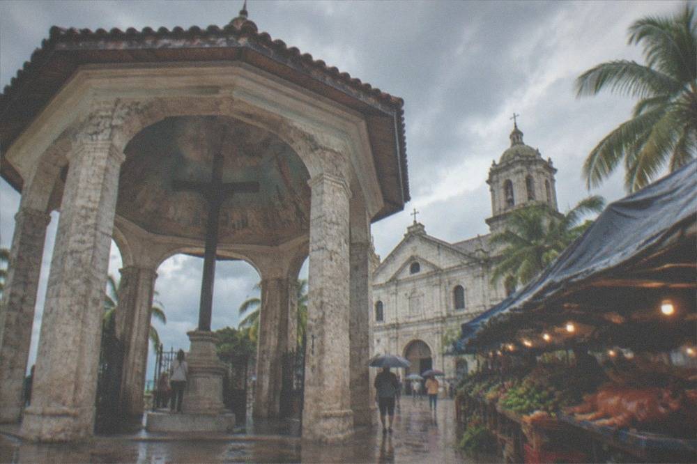 A covered market stall in Cebu with roast pig and fresh produce under a tarp awning