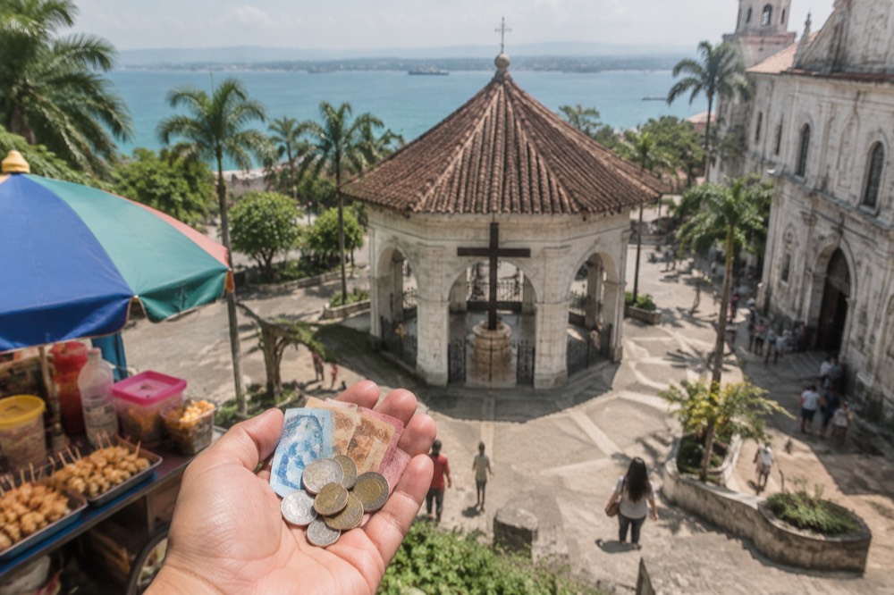 Small peso notes and coins held in a hand at an outdoor food stall in Cebu