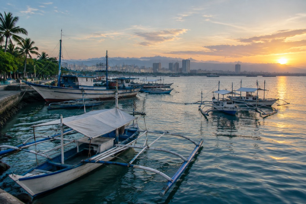Fishing boats and outrigger bangka boats moored along the Cebu City waterfront at dusk