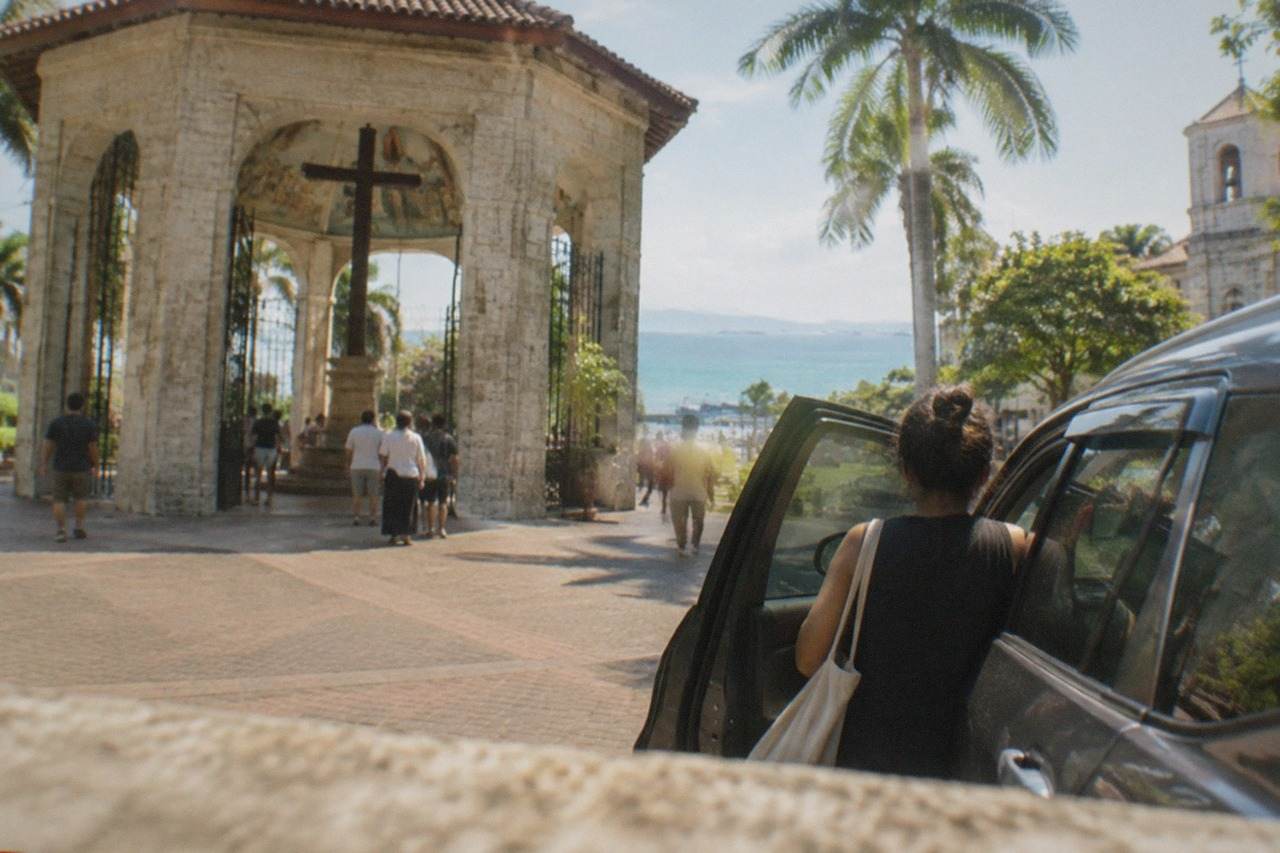 A passenger boarding a car at a pickup point on a busy street in Cebu City