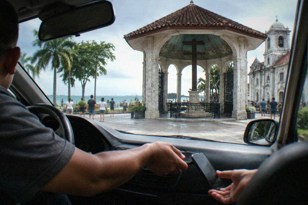 A driver handing a phone back to a passenger in the front seat of a car