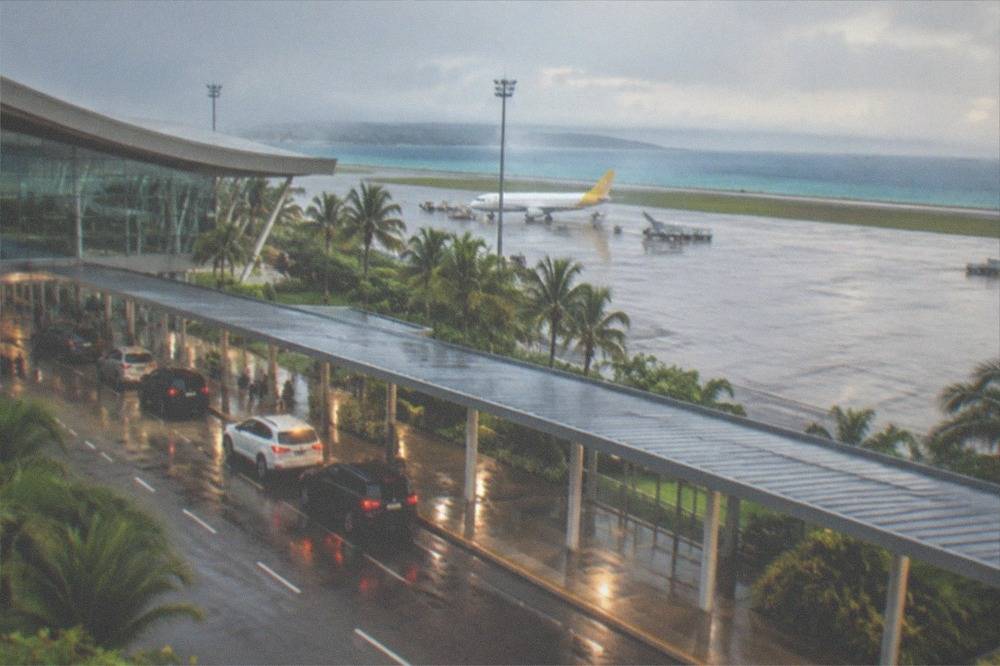 Cars waiting in a pickup lane outside a modern airport terminal at night