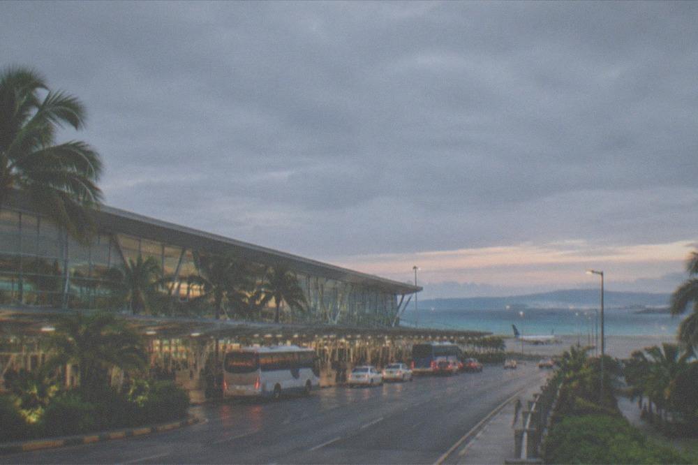 Airport terminal exterior with buses and taxis waiting at the kerb at dusk