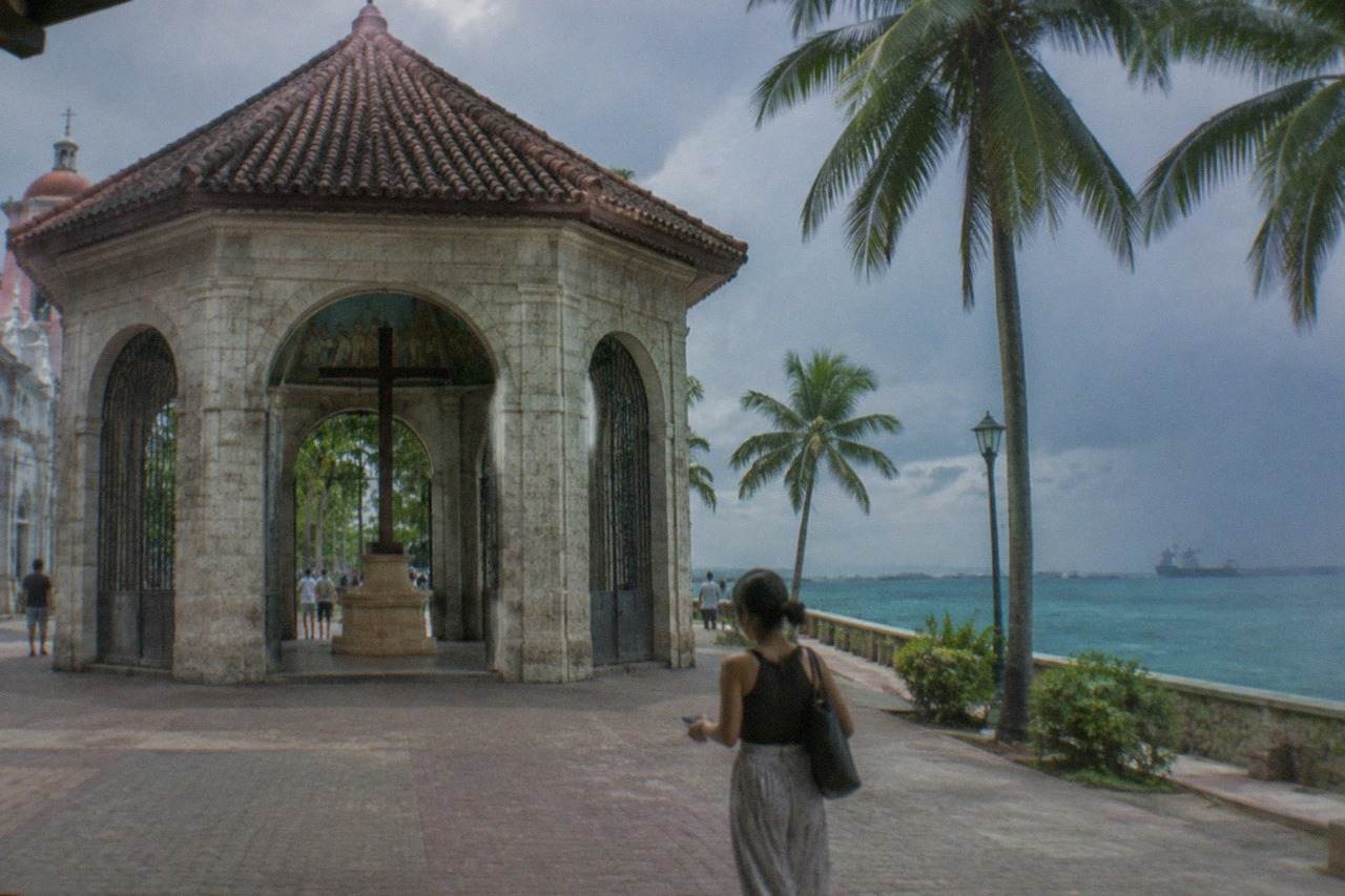Traveler holding a smartphone while walking along a waterfront promenade in Cebu