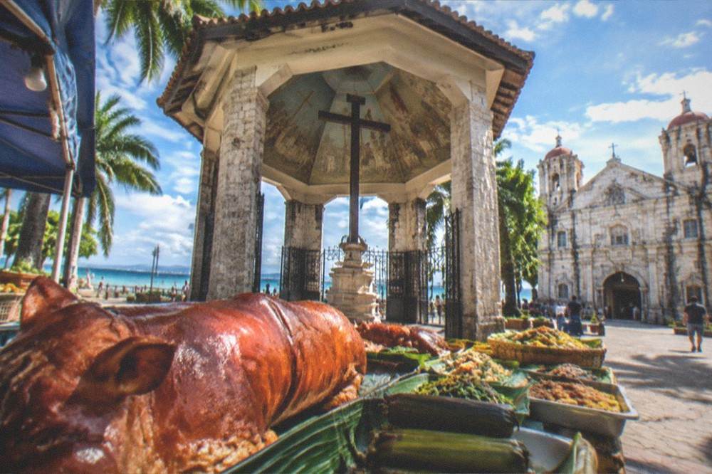 A market stall in Cebu piled with roasted pig and fresh local dishes