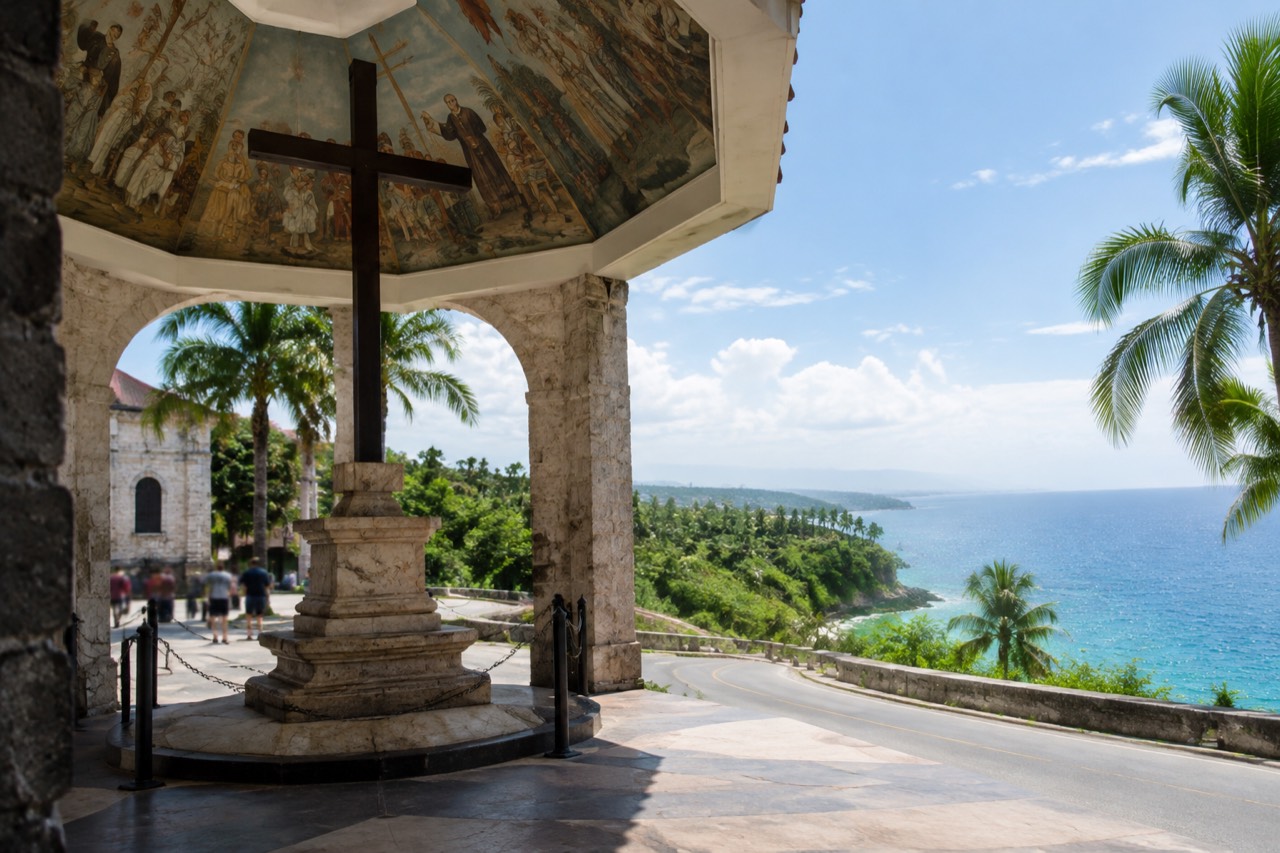 Coastal road winding along a green tropical cliffside above turquoise water on Cebu island