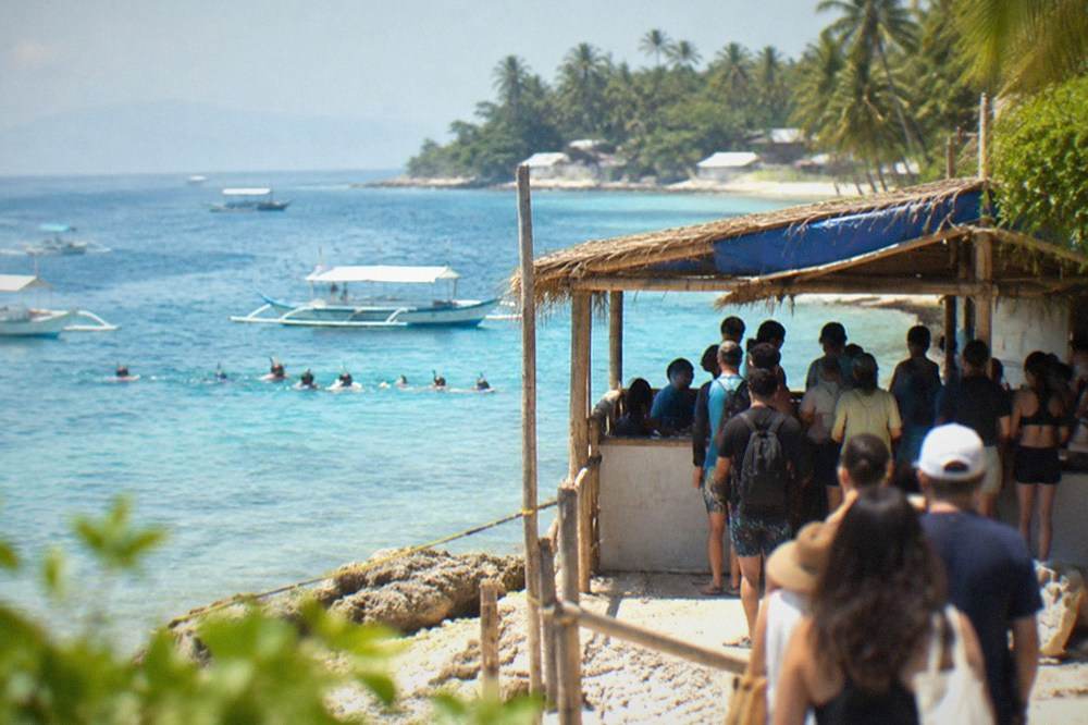 A registration kiosk and queue of visitors at the whale shark briefing area in Tan-awan, Oslob