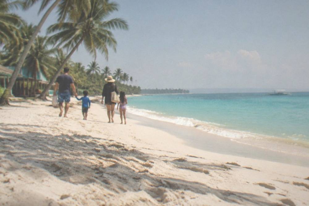 Family walking on white sand at Santa Fe beach on Bantayan Island