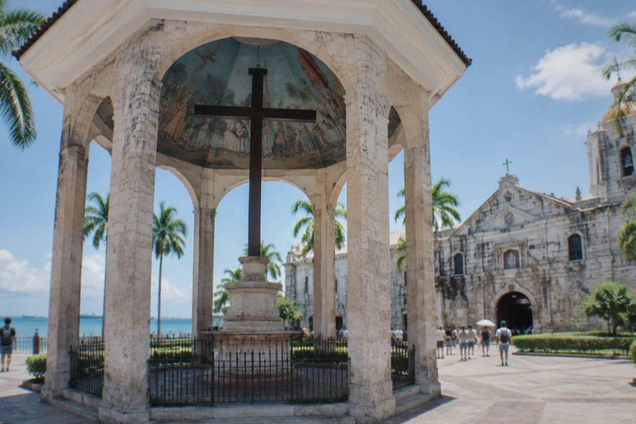 Cebu City heritage plaza with a historic stone church and palm trees under a bright sky
