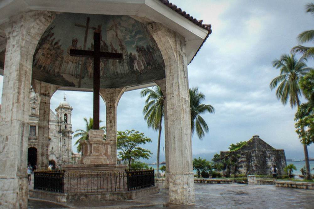 Facades of an old coral-stone church and a small triangular fort in Cebu City
