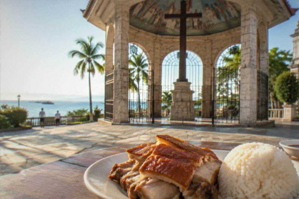 A plate of Cebu lechon with crispy skin beside rice at a local eatery
