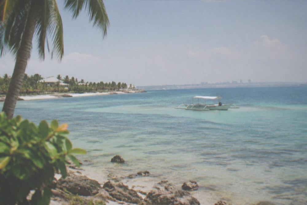 A small boat moored over a shallow sandbar near the Mactan islands