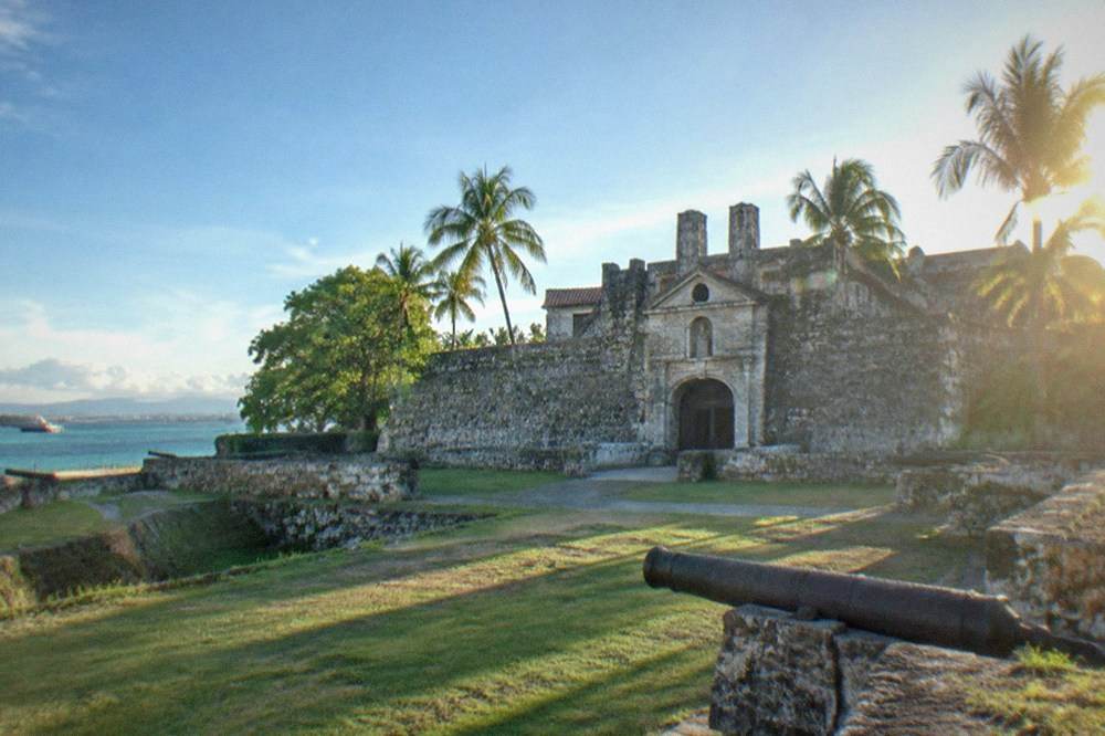 The historic coral stone gate and walls of Fort San Pedro in Cebu City under a blue sky