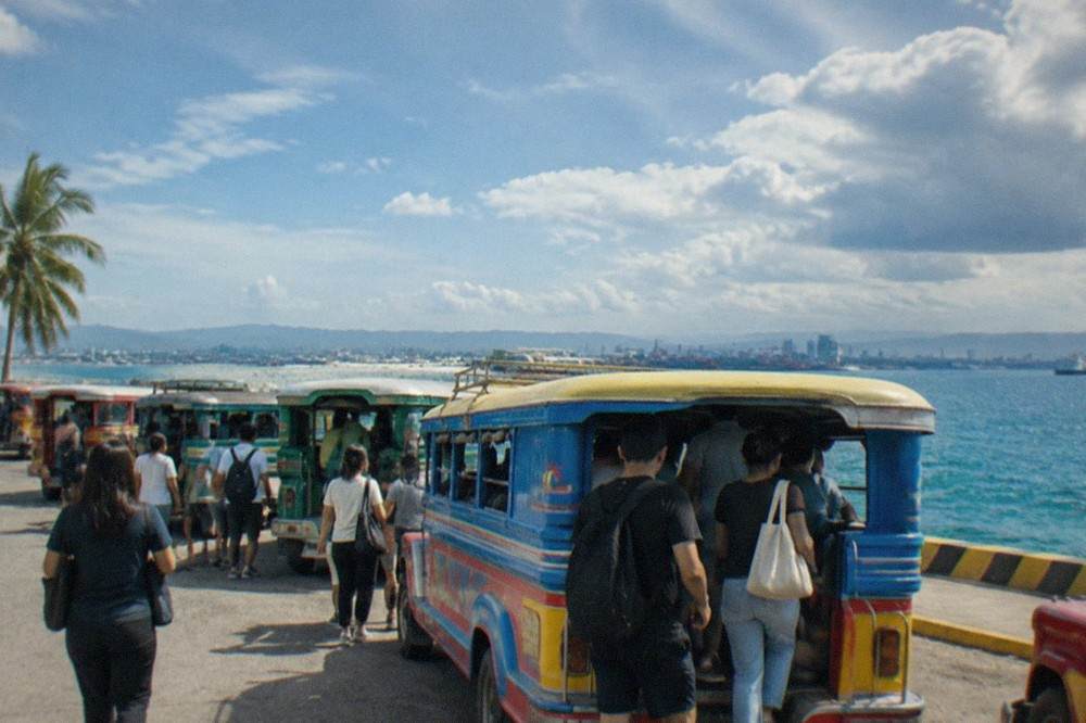 Passengers boarding colorful local jeepneys on a busy street in a Philippine city