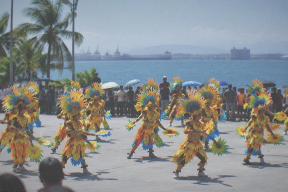 Street dancers in colorful costumes performing at a large Philippine festival parade