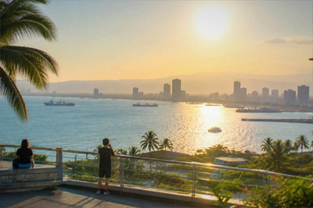 A viewing deck overlooking a tropical city and coastline at golden hour