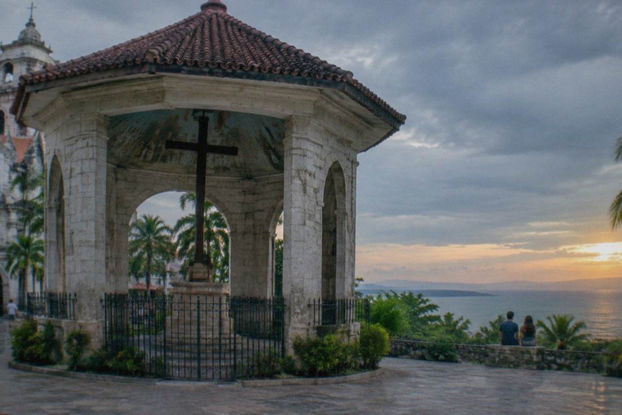 A couple watching the sunset over the sea from a hilltop viewpoint in Cebu