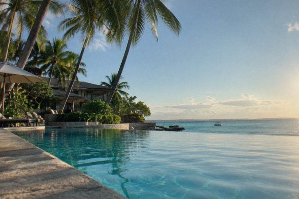 A beachfront resort pool overlooking calm turquoise water on Mactan Island