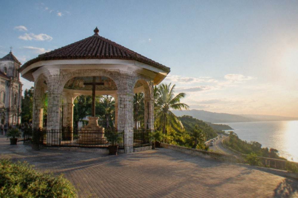A winding coastal road with green hills above the sea on the island of Cebu